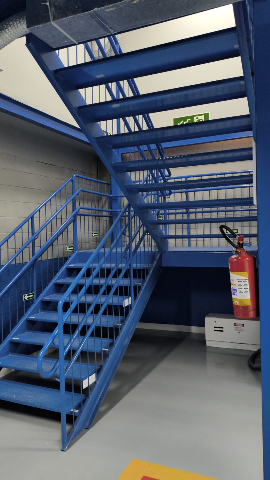 Escada metálica em U pintada de azul em interior industrial