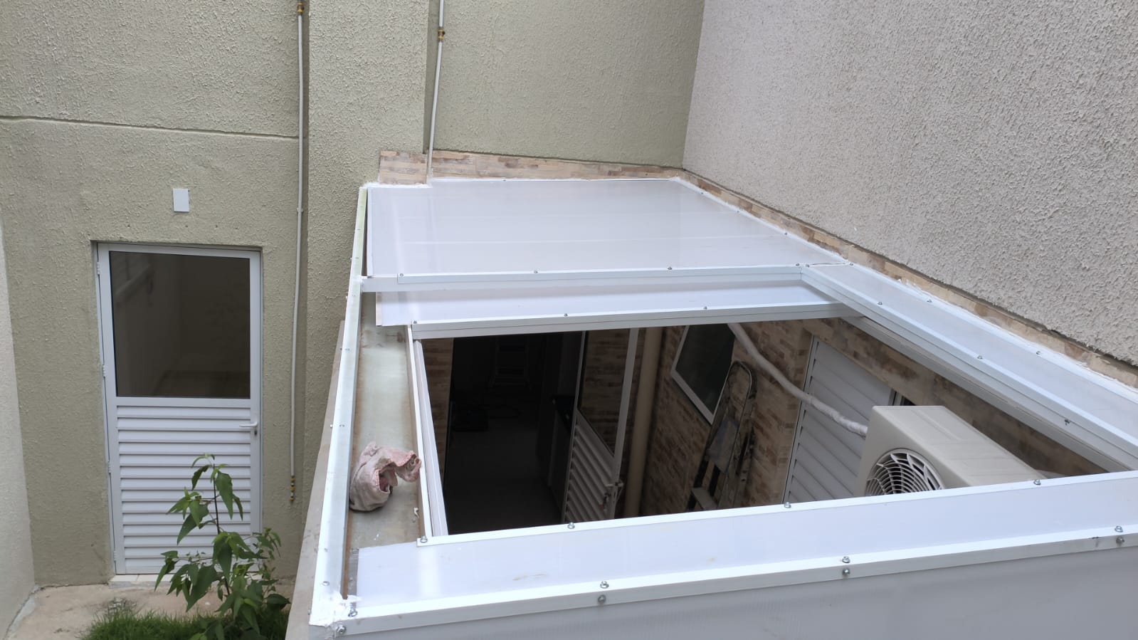 Cobertura de policarbonato branco instalada em pátio interno, vista de cima