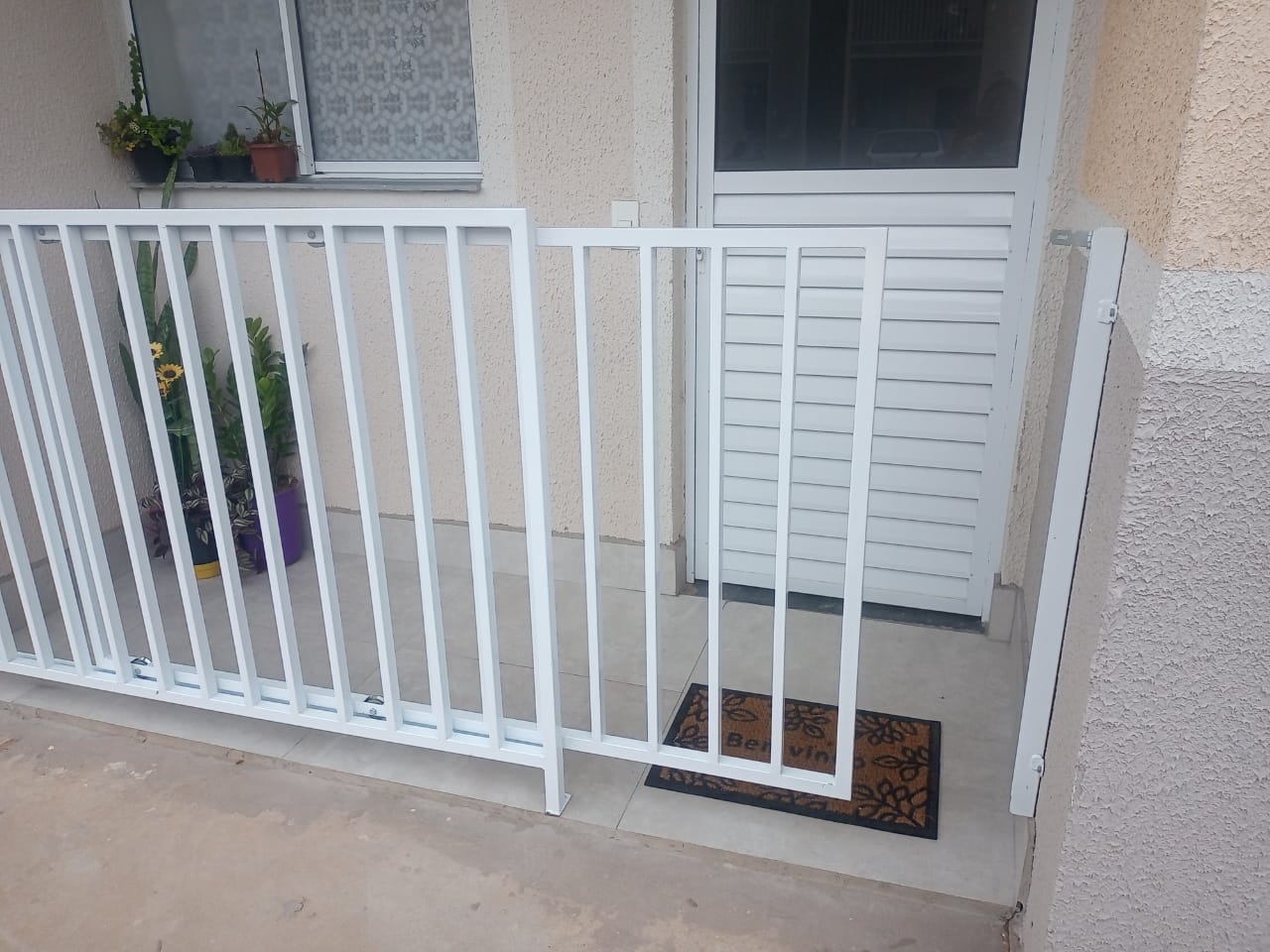 Portão branco de grades instalado na entrada de uma casa